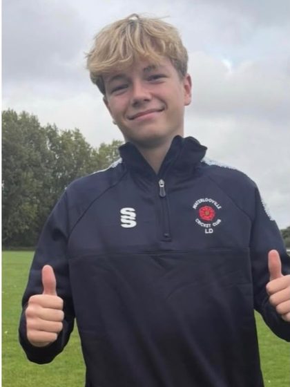 Louie in Waterlooville Cricket Club training kit, both
                      thumbs up, on the outfield